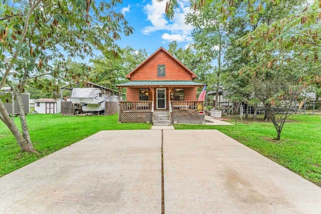 view of front of home featuring a front yard, a storage shed, and a porch