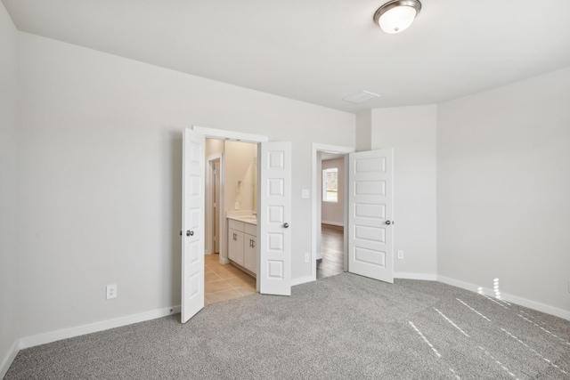 unfurnished bedroom with light colored carpet and ensuite bath