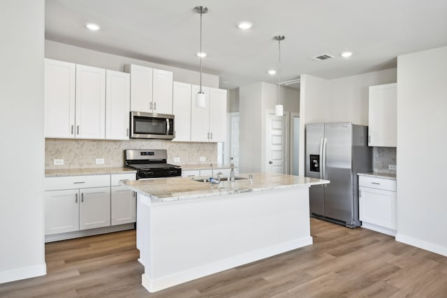 kitchen with light hardwood / wood-style flooring, white cabinets, hanging light fixtures, and appliances with stainless steel finishes