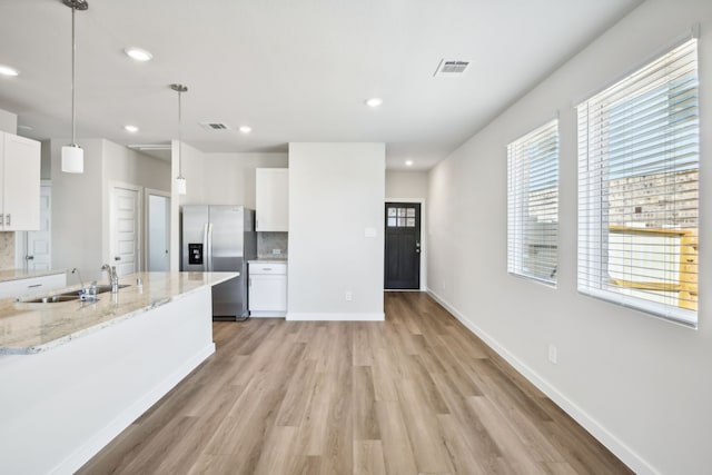 kitchen featuring white cabinets, stainless steel fridge, light hardwood / wood-style flooring, and sink