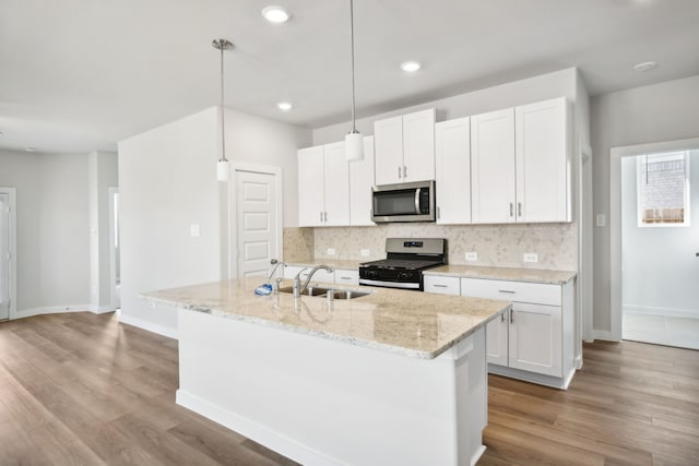 kitchen featuring appliances with stainless steel finishes, white cabinetry, hanging light fixtures, and sink