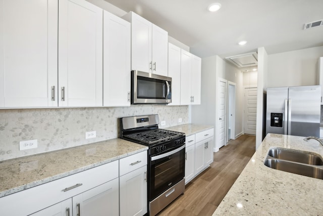 kitchen featuring white cabinetry, sink, light hardwood / wood-style floors, and appliances with stainless steel finishes