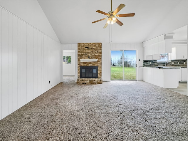 unfurnished living room featuring a fireplace, light colored carpet, a healthy amount of sunlight, and ceiling fan