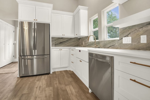 kitchen with hardwood / wood-style floors, appliances with stainless steel finishes, white cabinetry, and tasteful backsplash