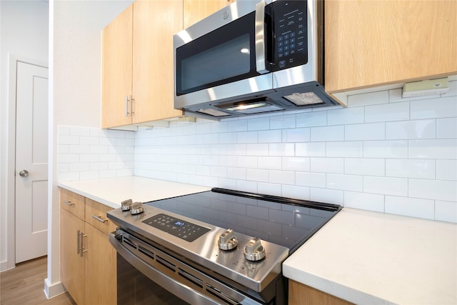 kitchen featuring stainless steel appliances, light brown cabinets, backsplash, and light hardwood / wood-style floors