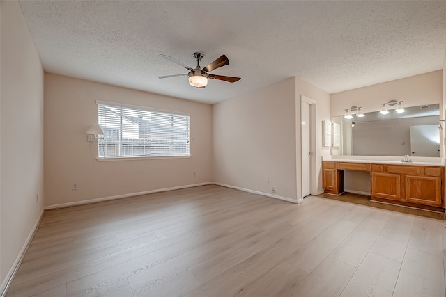 unfurnished bedroom with a textured ceiling, built in desk, and light hardwood / wood-style floors