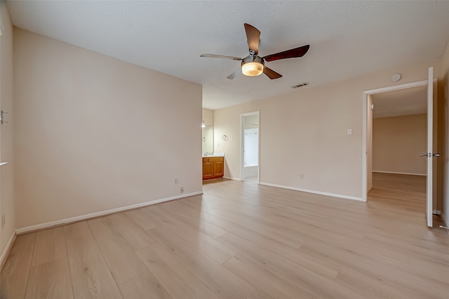 unfurnished bedroom with a textured ceiling, light hardwood / wood-style flooring, ensuite bathroom, and ceiling fan