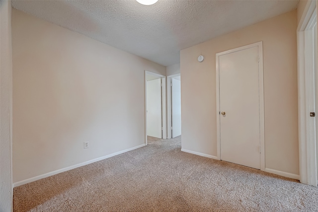 unfurnished bedroom featuring light carpet, a textured ceiling, and a closet