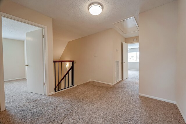 bonus room featuring lofted ceiling, light carpet, and a textured ceiling