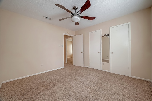 unfurnished bedroom featuring ceiling fan, light carpet, and a textured ceiling