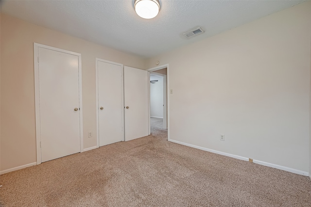 unfurnished bedroom featuring a textured ceiling and light carpet