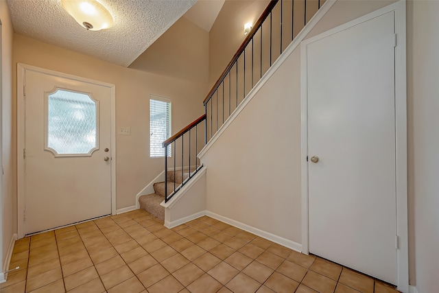 entrance foyer featuring a textured ceiling, stairs, and baseboards