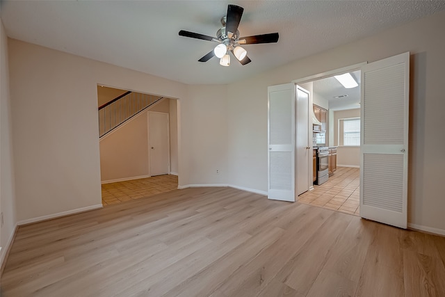 empty room featuring a textured ceiling, light hardwood / wood-style flooring, and ceiling fan