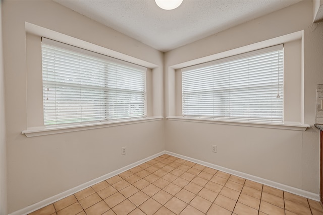 tiled spare room featuring a textured ceiling