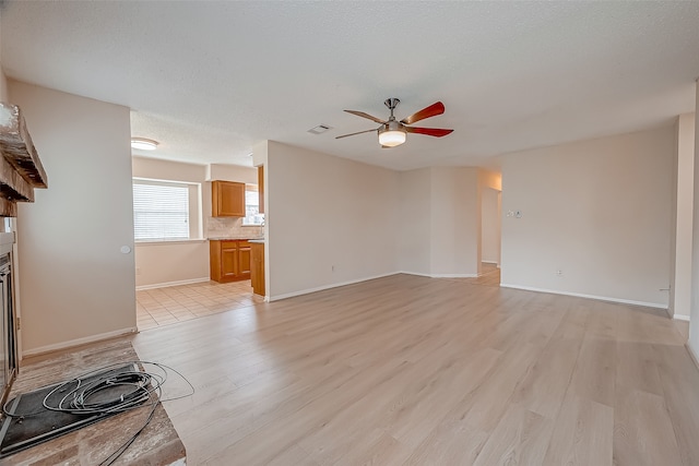 unfurnished living room featuring light wood-type flooring, a textured ceiling, and ceiling fan