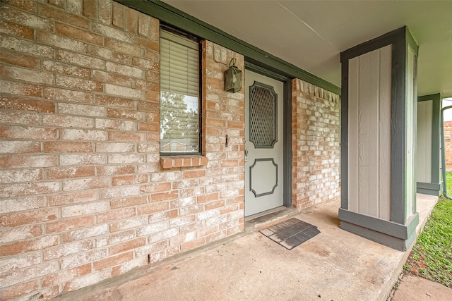 property entrance featuring brick siding and covered porch