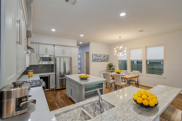 kitchen with pendant lighting, a center island, stainless steel appliances, dark hardwood / wood-style flooring, and light stone countertops