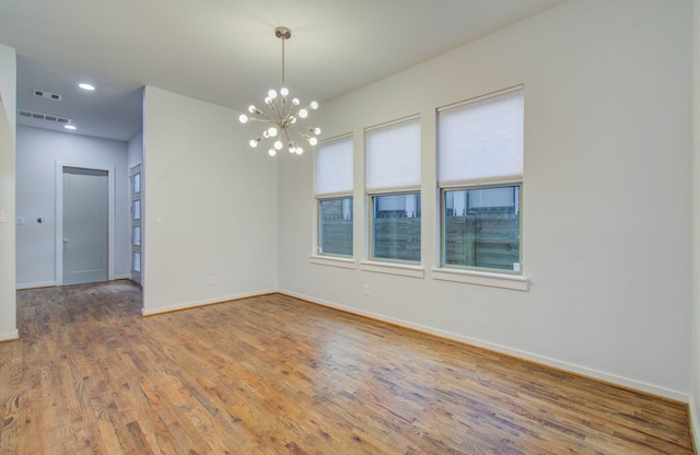 empty room featuring an inviting chandelier and wood-type flooring