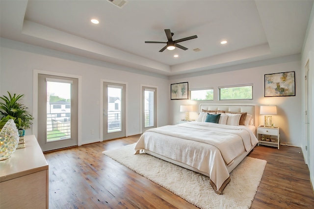 bedroom with access to outside, dark hardwood / wood-style flooring, multiple windows, and ceiling fan