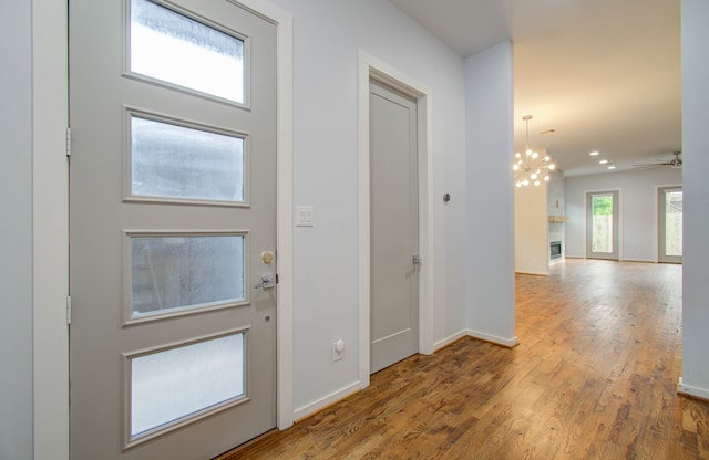 foyer entrance featuring ceiling fan with notable chandelier and wood-type flooring