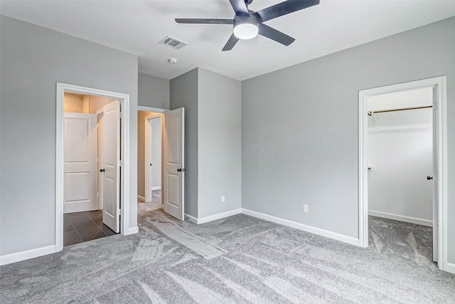 unfurnished bedroom with a spacious closet, ceiling fan, and carpet