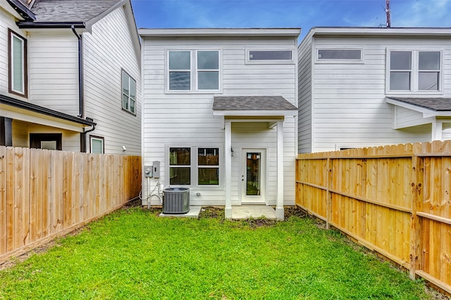 rear view of house with a lawn and central AC unit