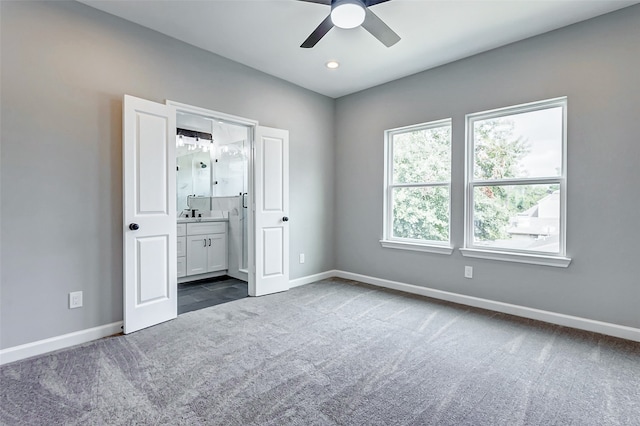 unfurnished bedroom with carpet flooring, ceiling fan, and ensuite bath