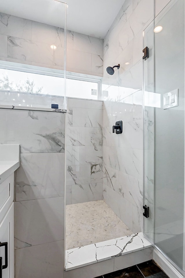 bathroom with a shower with shower door and vanity