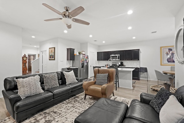 living area featuring light wood-type flooring, visible vents, recessed lighting, stairway, and ceiling fan