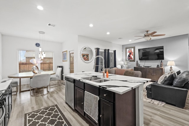 kitchen with light wood finished floors, visible vents, a sink, open floor plan, and stainless steel dishwasher