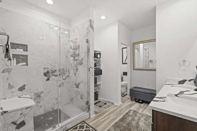 bathroom with toilet, wood-type flooring, a shower with door, and vanity