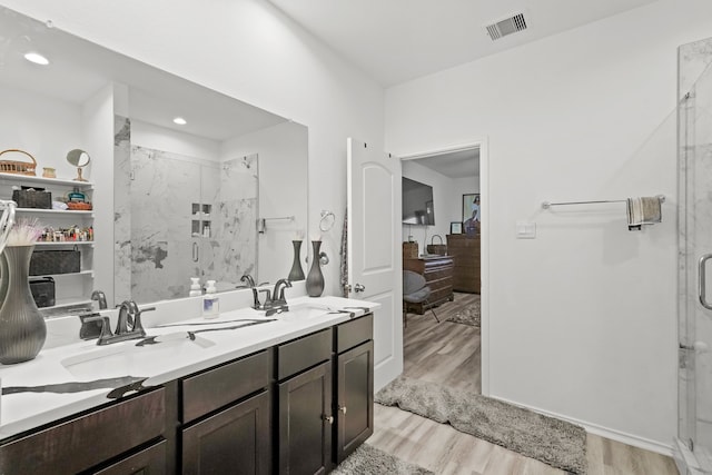 bathroom with hardwood / wood-style floors, vanity, and a shower with shower door