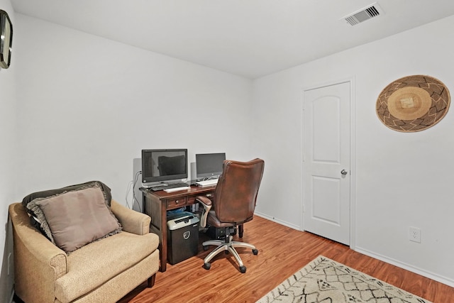 office area with visible vents, baseboards, and wood finished floors