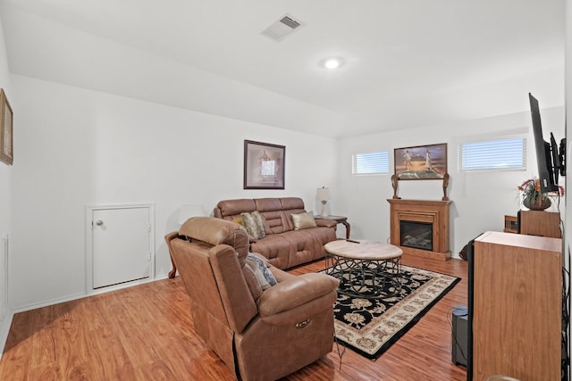 living area with visible vents, recessed lighting, light wood-style floors, and a glass covered fireplace