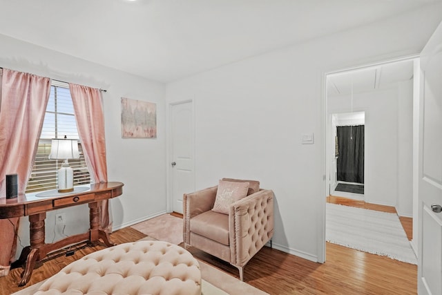 living area with baseboards, light wood-style floors, and attic access