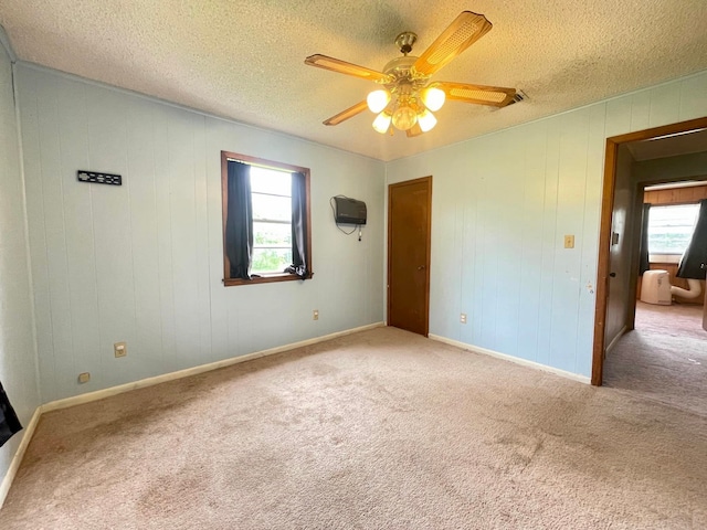 unfurnished bedroom featuring light carpet, a textured ceiling, and ceiling fan