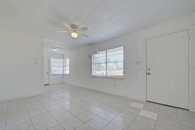 interior space with ceiling fan, a wall mounted air conditioner, light tile patterned floors, and a healthy amount of sunlight