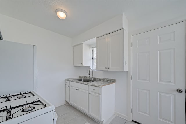 kitchen featuring light tile patterned floors, white cabinets, sink, and white gas range