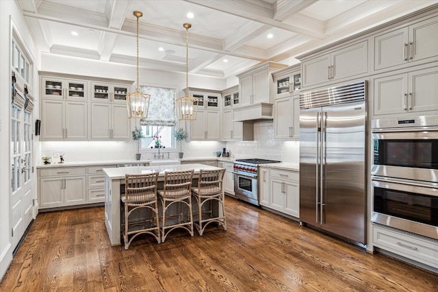 kitchen with high end appliances, beam ceiling, light countertops, and dark wood finished floors