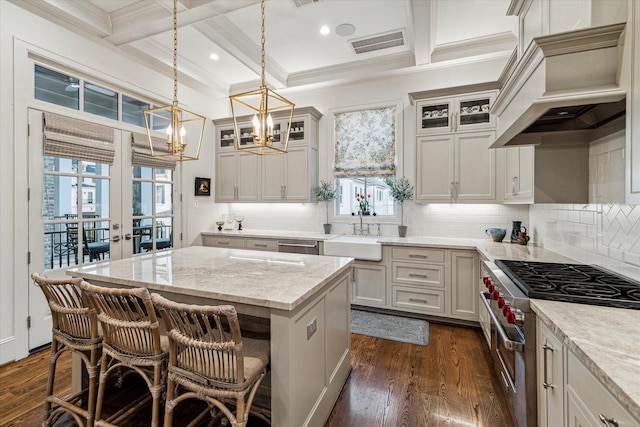 kitchen with custom exhaust hood, visible vents, high end stainless steel range oven, dark wood-type flooring, and a sink