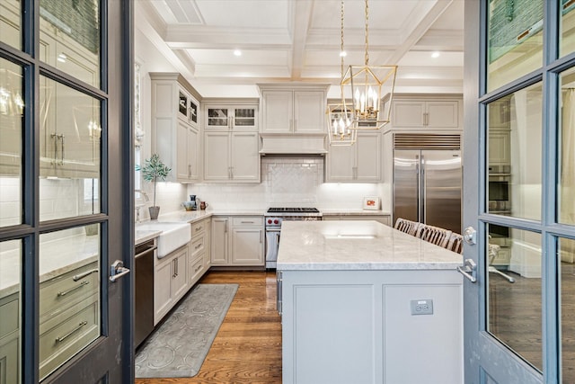 kitchen featuring a kitchen island, a sink, high quality appliances, backsplash, and dark wood finished floors