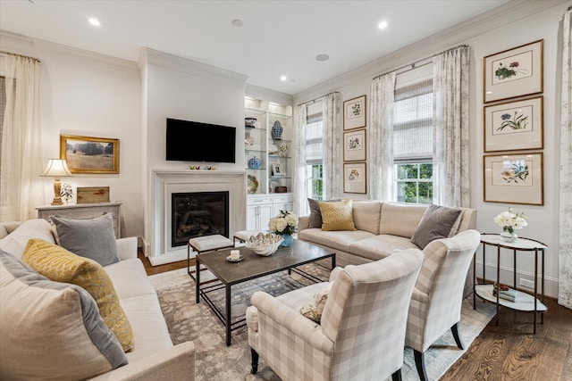 living area featuring baseboards, a glass covered fireplace, wood finished floors, crown molding, and recessed lighting