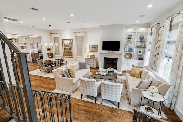 living area featuring crown molding, visible vents, wood finished floors, and a glass covered fireplace