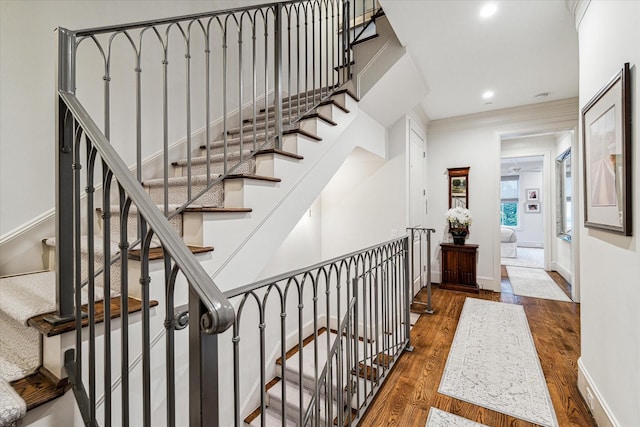 stairway featuring baseboards, wood finished floors, and recessed lighting