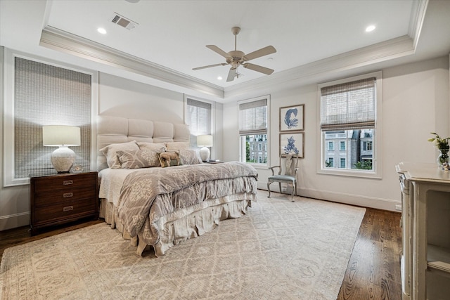 bedroom featuring ornamental molding, a raised ceiling, visible vents, and wood finished floors