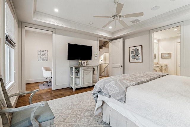 bedroom featuring ornamental molding, a raised ceiling, visible vents, and wood finished floors