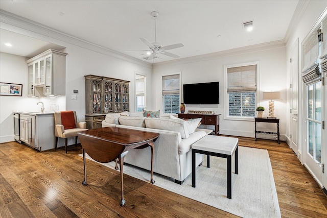 living room featuring visible vents, crown molding, baseboards, and wood finished floors