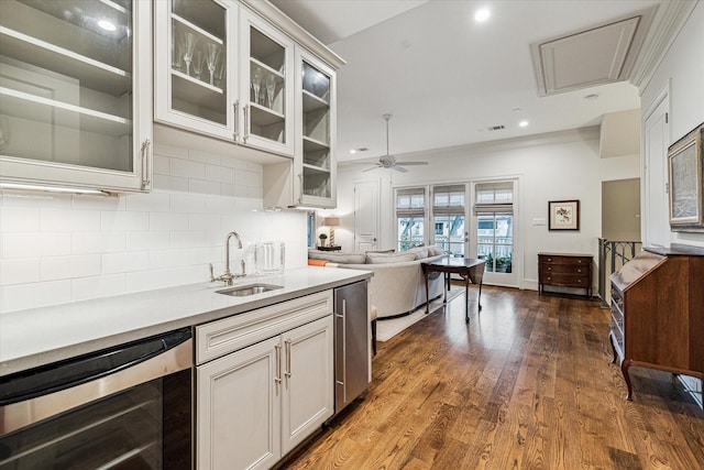 kitchen with wine cooler, light countertops, decorative backsplash, dark wood-type flooring, and a sink