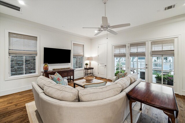 living area featuring baseboards, visible vents, dark wood finished floors, and crown molding