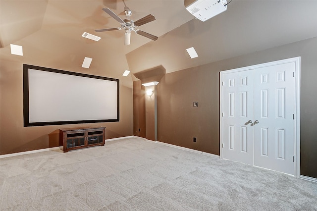 carpeted home theater room with visible vents, baseboards, a ceiling fan, and vaulted ceiling